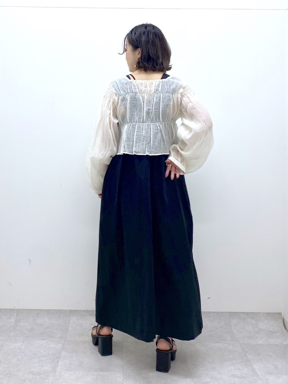 ブラック系のジャンパースカート、ホワイト系のシャツ/ブラウス、その他のサンダルを着用したレディースの夏コーディネートの4枚目の写真