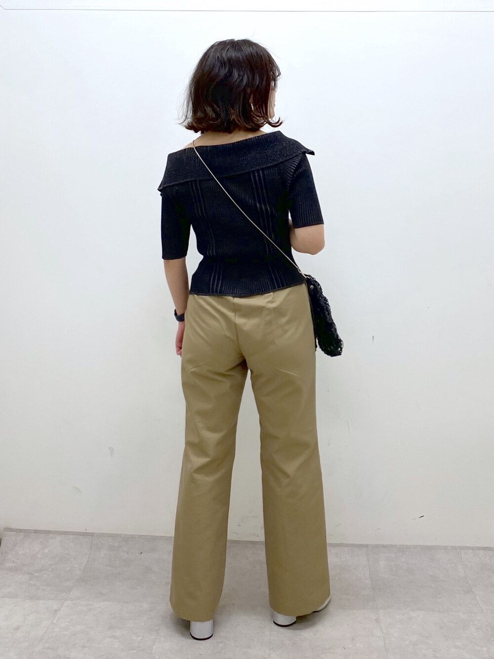 ブラック系のニット/セーター、ベージュ系のチノパンツ、ブラック系のショルダーバッグを着用したレディースの春コーディネートの6枚目の写真