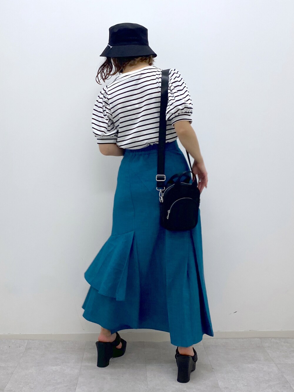 ブルー系のスカート、ブラック系のサンダル、ブラック系のショルダーバッグを着用したレディースの夏コーディネートの3枚目の写真