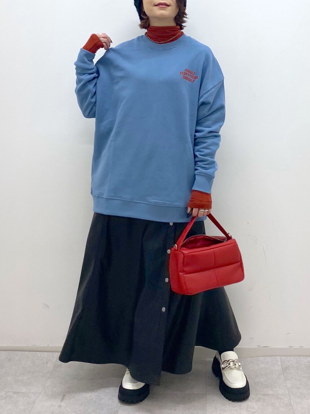 ブラック系のスカート、ホワイト系のシューズ、レッド系のショルダーバッグを着用したレディースの秋コーディネートの5枚目の写真