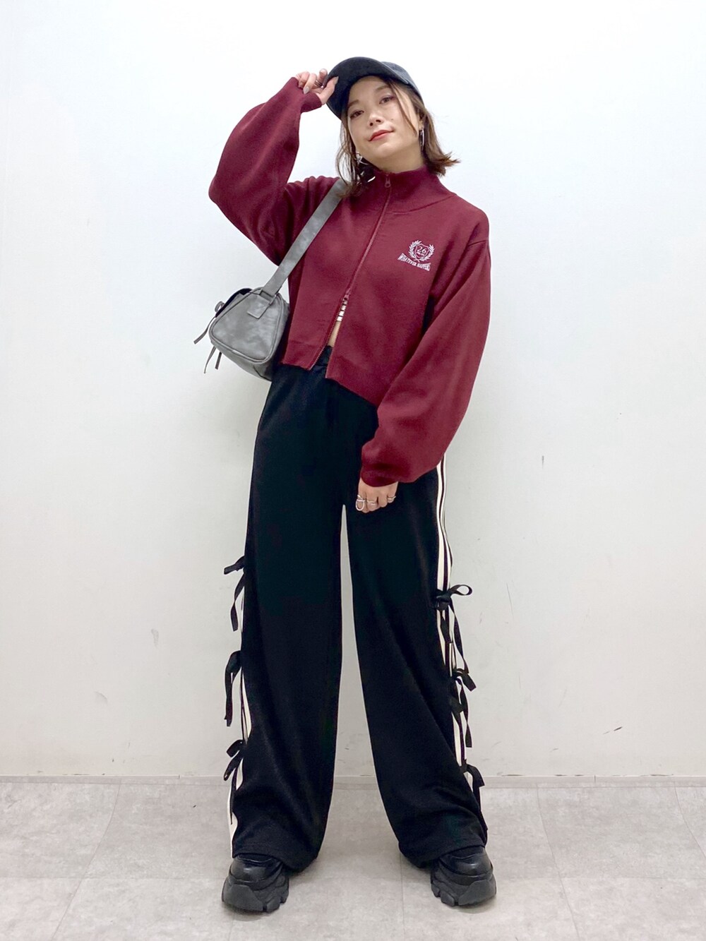 レッド系のニット/セーター、ブラック系のその他パンツ、ブラック系のブーツを着用したレディースの秋コーディネートの5枚目の写真