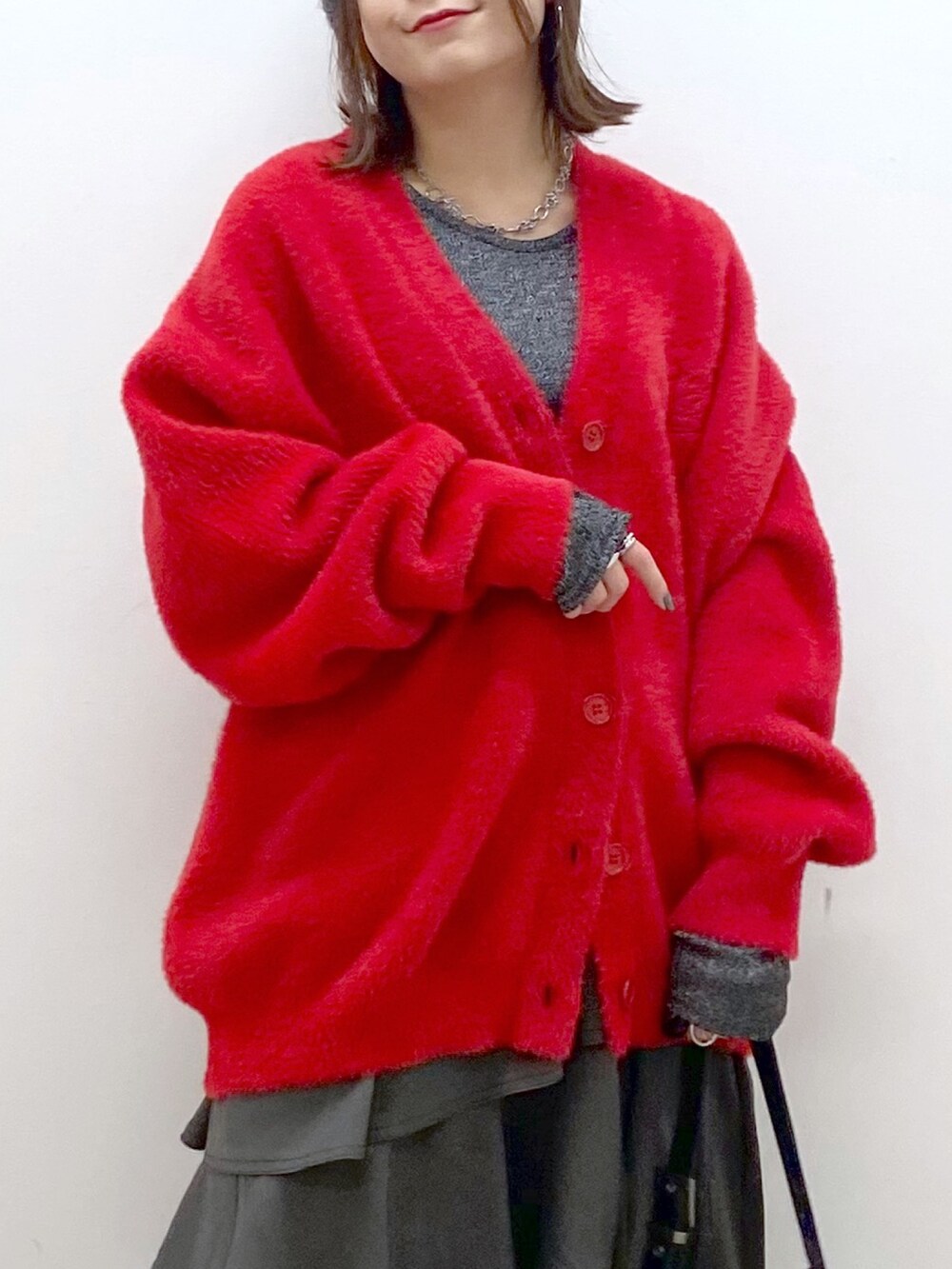 レッド系のカーディガン/ボレロ、シルバー系のTシャツ/カットソー、ブラウン系のスカートを着用したレディースの秋コーディネートの2枚目の写真