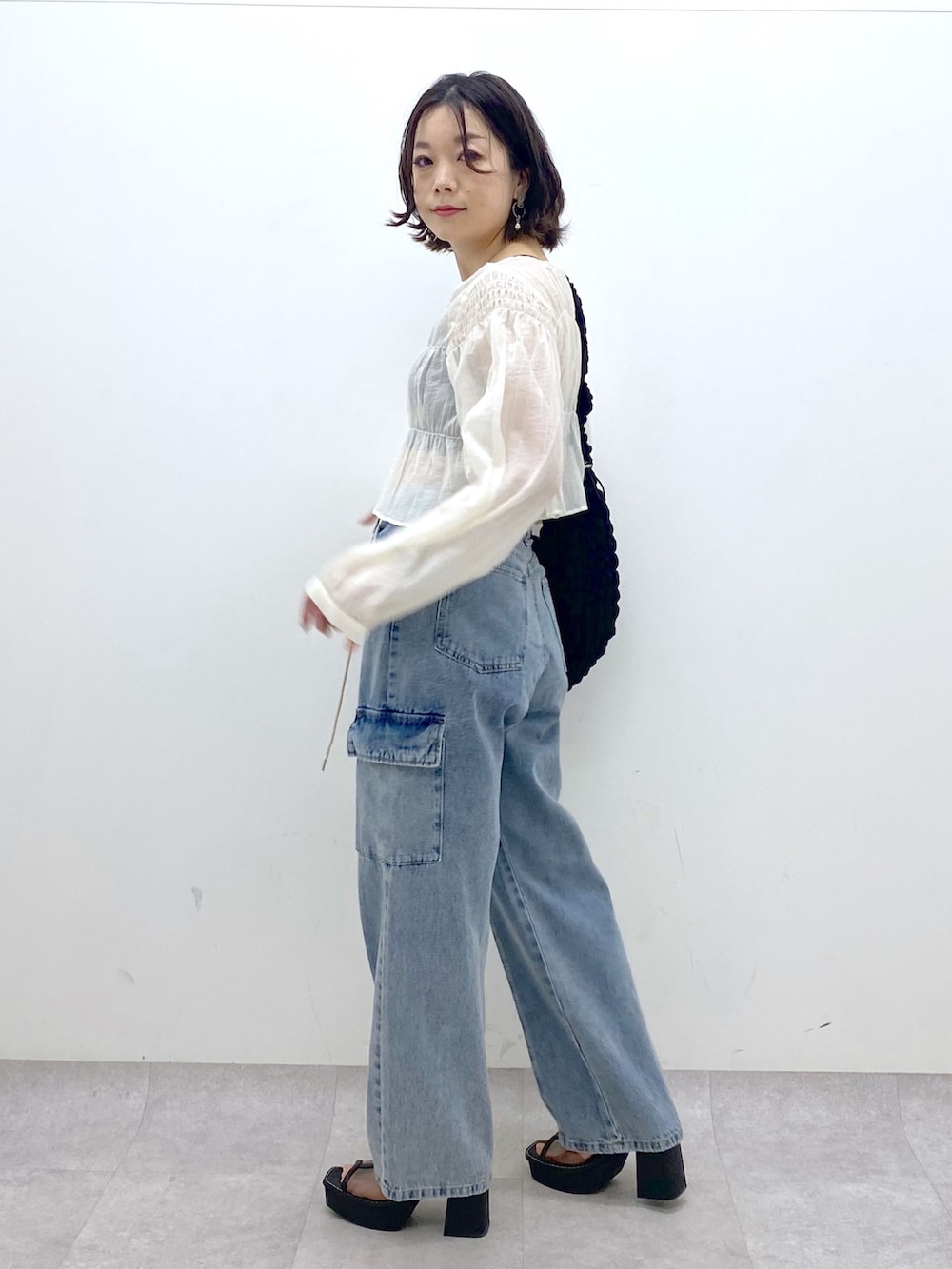ホワイト系のシャツ/ブラウス、ブルー系のデニムパンツ、ブラック系のバッグを着用したレディースの春コーディネートの2枚目の写真