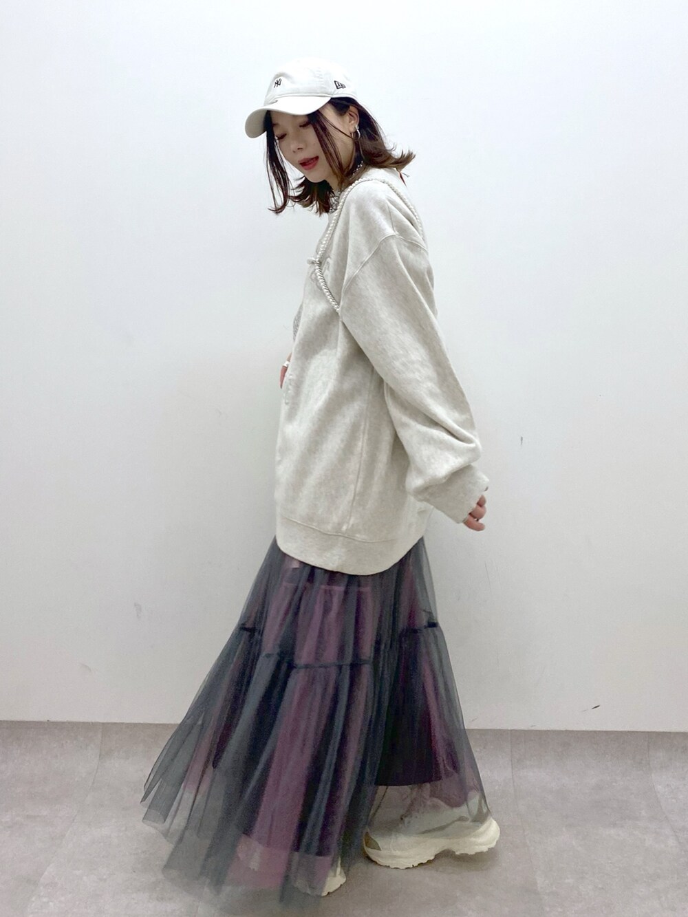 ベージュ系のスウェット、シルバー系のショルダーバッグ、グレー系のスカートを着用したレディースの春コーディネートの5枚目の写真