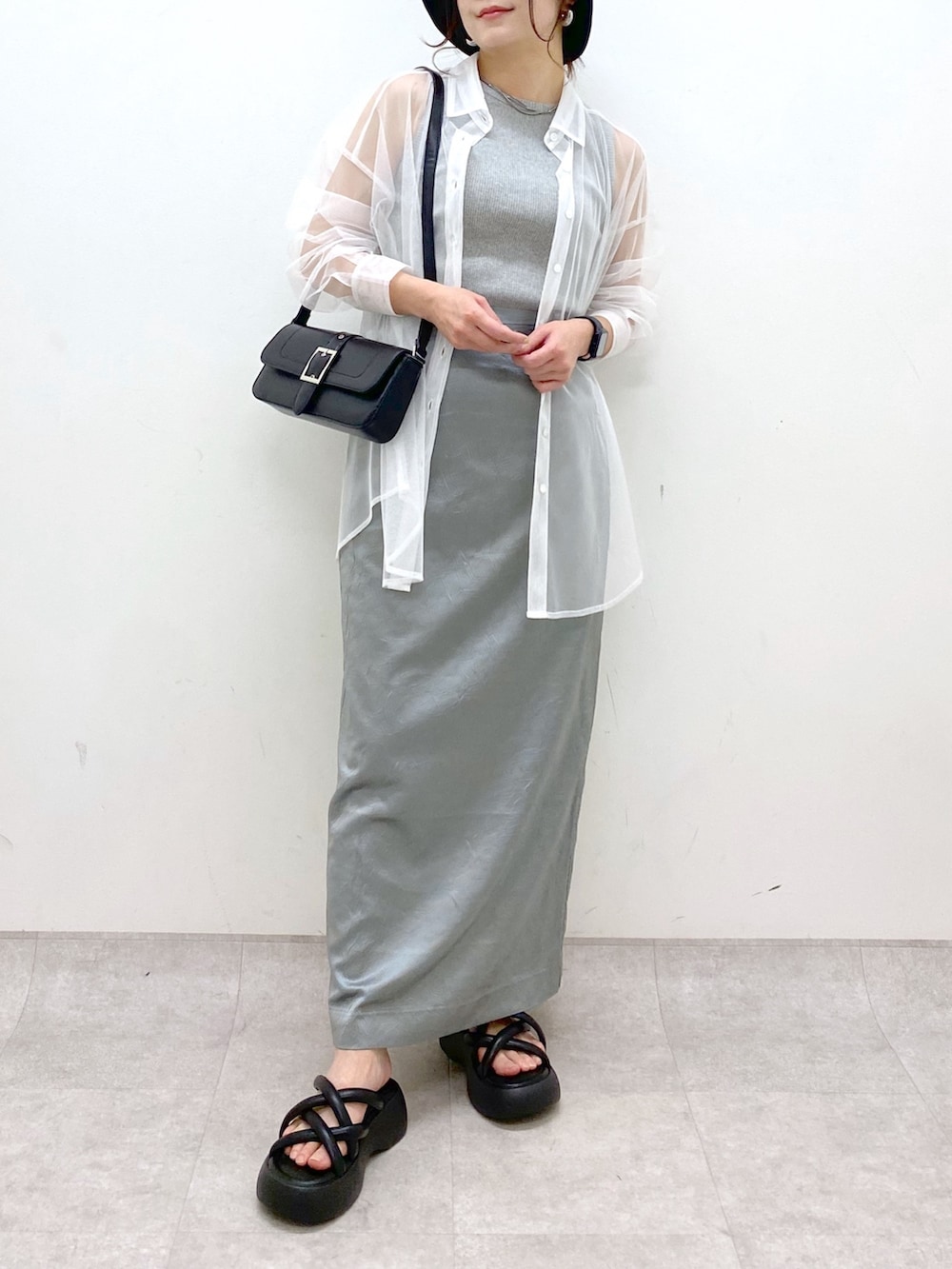 ブルー系のスカート、ブラック系のハンドバッグ、ブラック系のサンダルを着用したレディースの春コーディネートの3枚目の写真