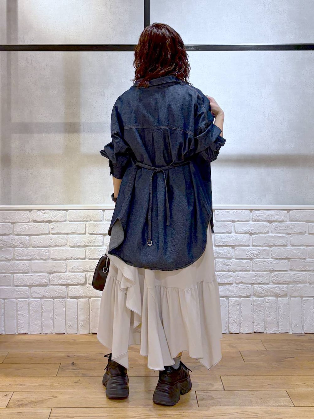 ブラック系のスニーカー、ベージュ系のスカート、ブラック系のボストンバッグを着用したレディースの春コーディネートの6枚目の写真