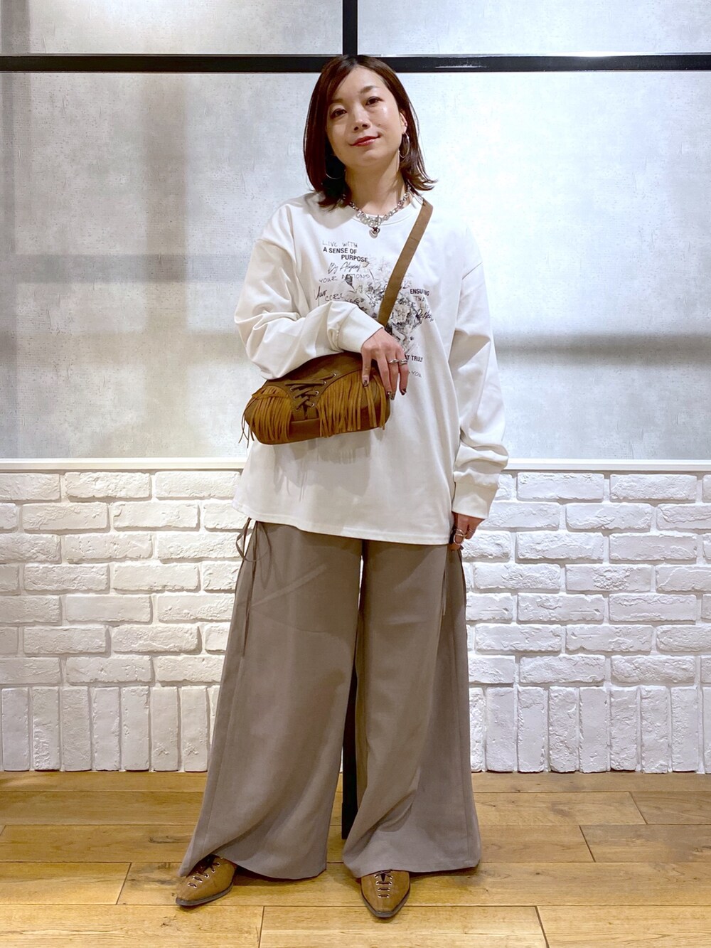 ブラウン系のスラックス、ベージュ系のショルダーバッグ、ブラウン系のパンプスを着用したレディースの春コーディネートの7枚目の写真