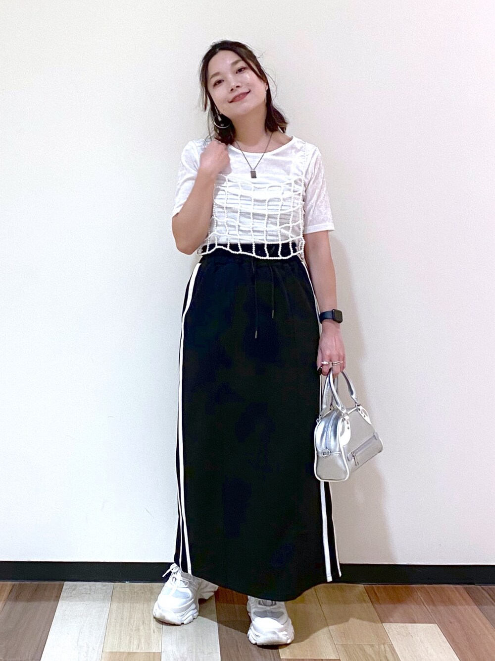 ブラック系のスカート、シルバー系のショルダーバッグ、ホワイト系のスニーカーを着用したレディースの夏コーディネートの4枚目の写真