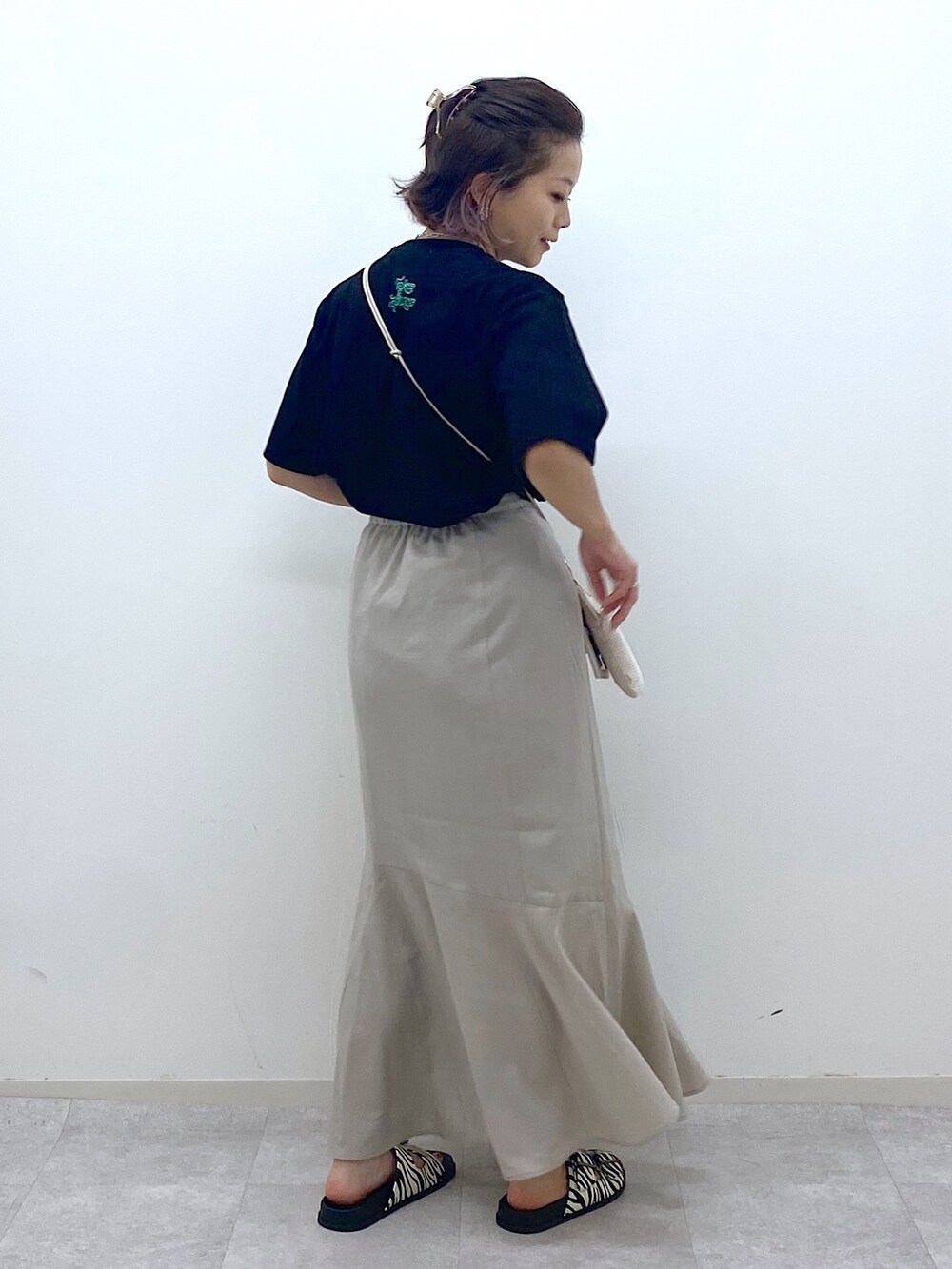 ベージュ系のショルダーバッグ、ベージュ系のスカート、ブラック系のTシャツ/カットソーを着用したレディースの夏コーディネートの3枚目の写真