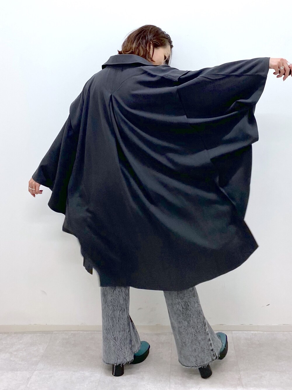 ブラック系のデニムパンツ、グレー系のポンチョ、ブラック系のトップスを着用したレディースの夏コーディネートの3枚目の写真