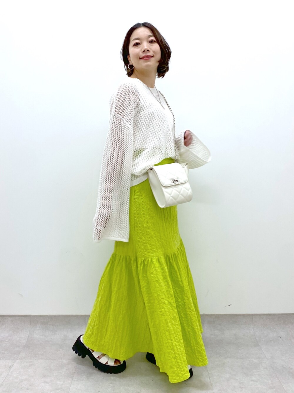 イエロー系のスカート、ホワイト系のバッグ、ホワイト系のトップスを着用したレディースの春コーディネートの5枚目の写真
