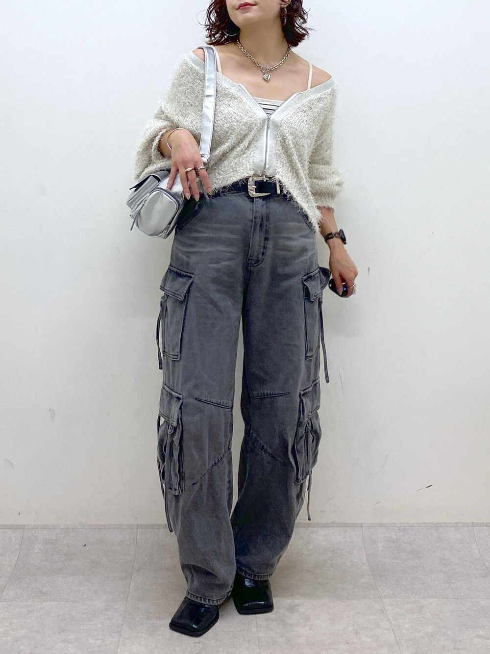 ブラック系のデニムパンツ、ブラック系のブーツ、シルバー系のショルダーバッグを着用したレディースの秋コーディネートの3枚目の写真