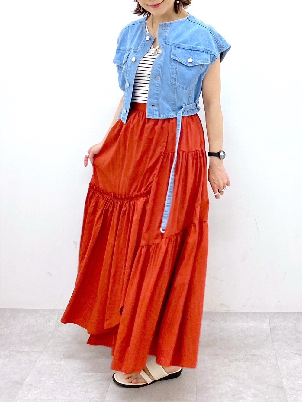 オレンジ系のスカート、ブルー系のその他アウター、ブラック系のキャミソールを着用したレディースの夏コーディネートの4枚目の写真