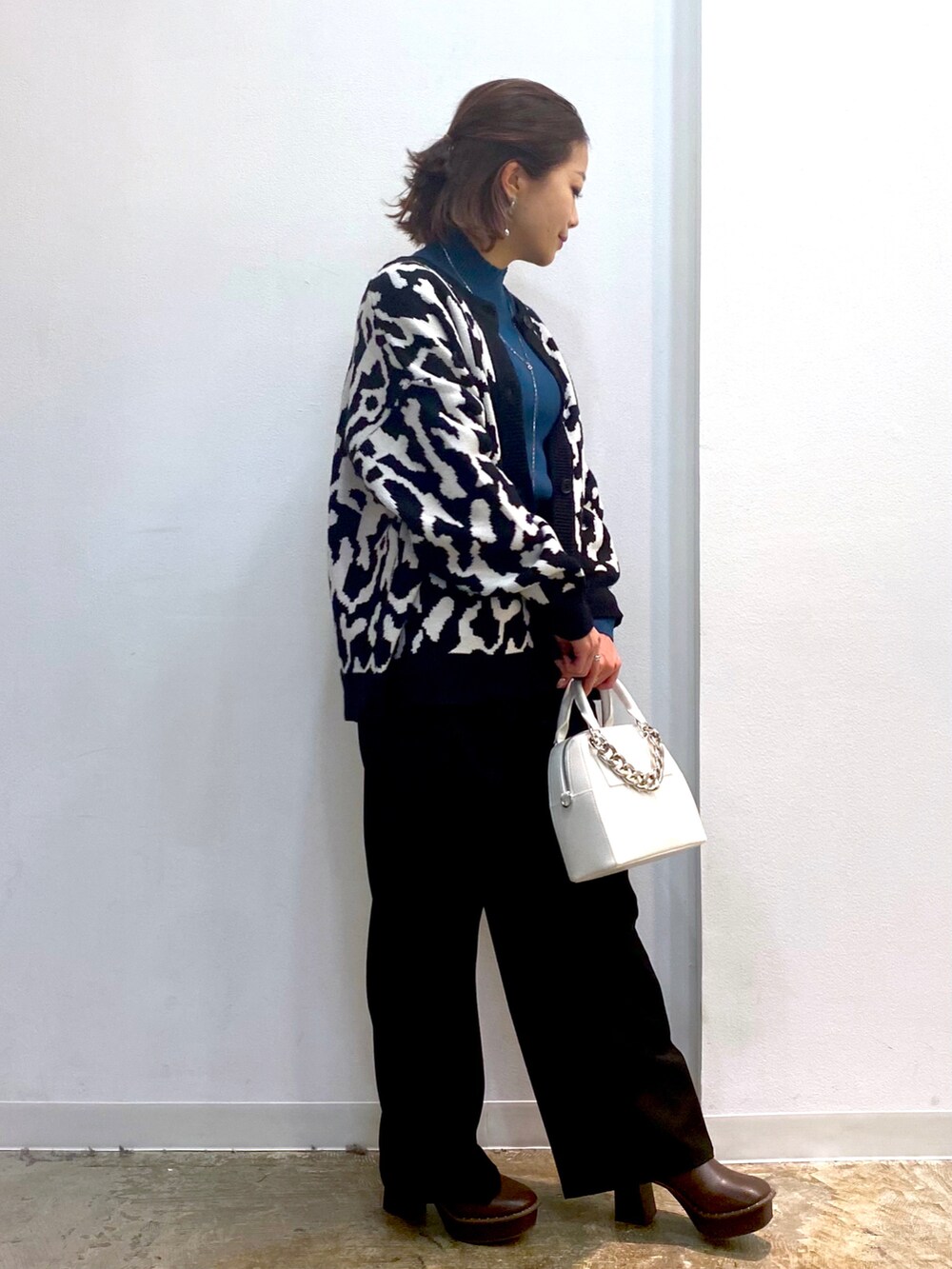 グリーン系のニット/セーター、ブラック系のニット/セーター、ブラック系のスラックスを着用したレディースの秋コーディネートの3枚目の写真