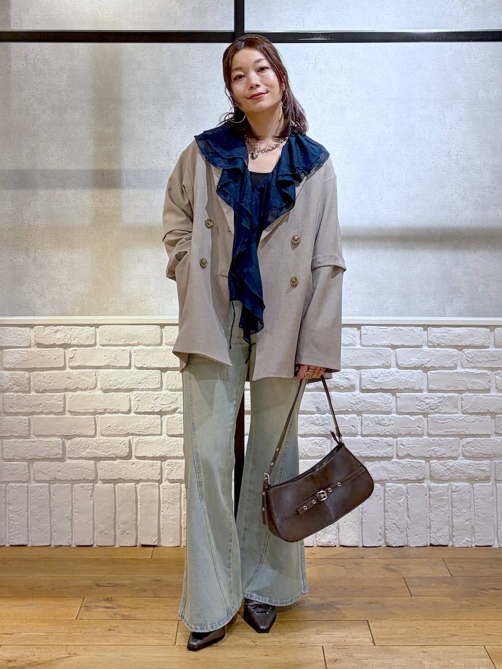 ブラック系のキャミソール、ブルー系のデニムパンツ、ブラウン系のハンドバッグを着用したレディースの春コーディネートの9枚目の写真