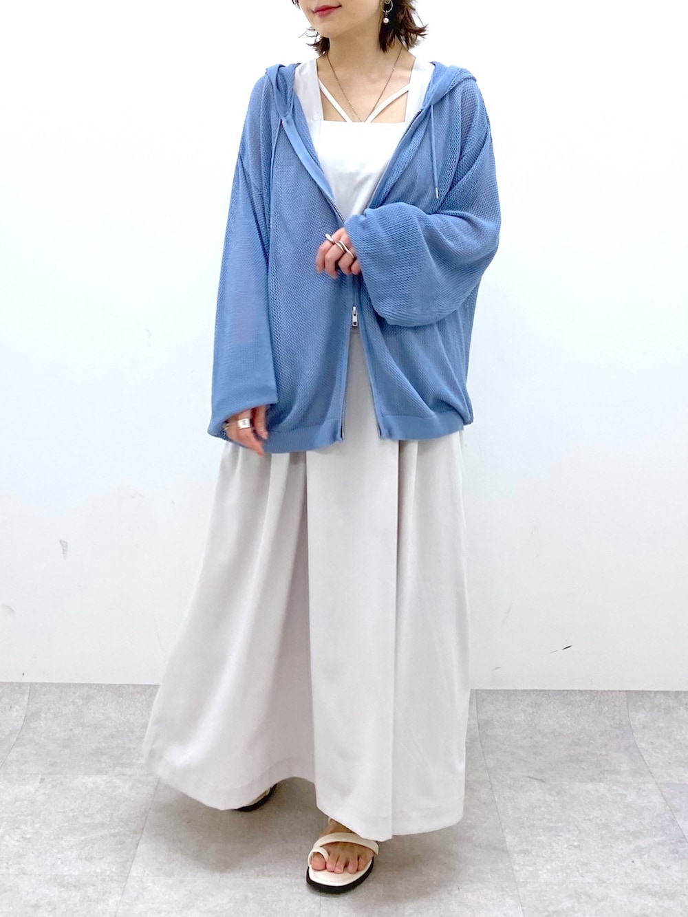 ベージュ系のジャンパースカート、ブルー系のニット/セーター、ブラック系のキャミソールを着用したレディースの夏コーディネートの5枚目の写真