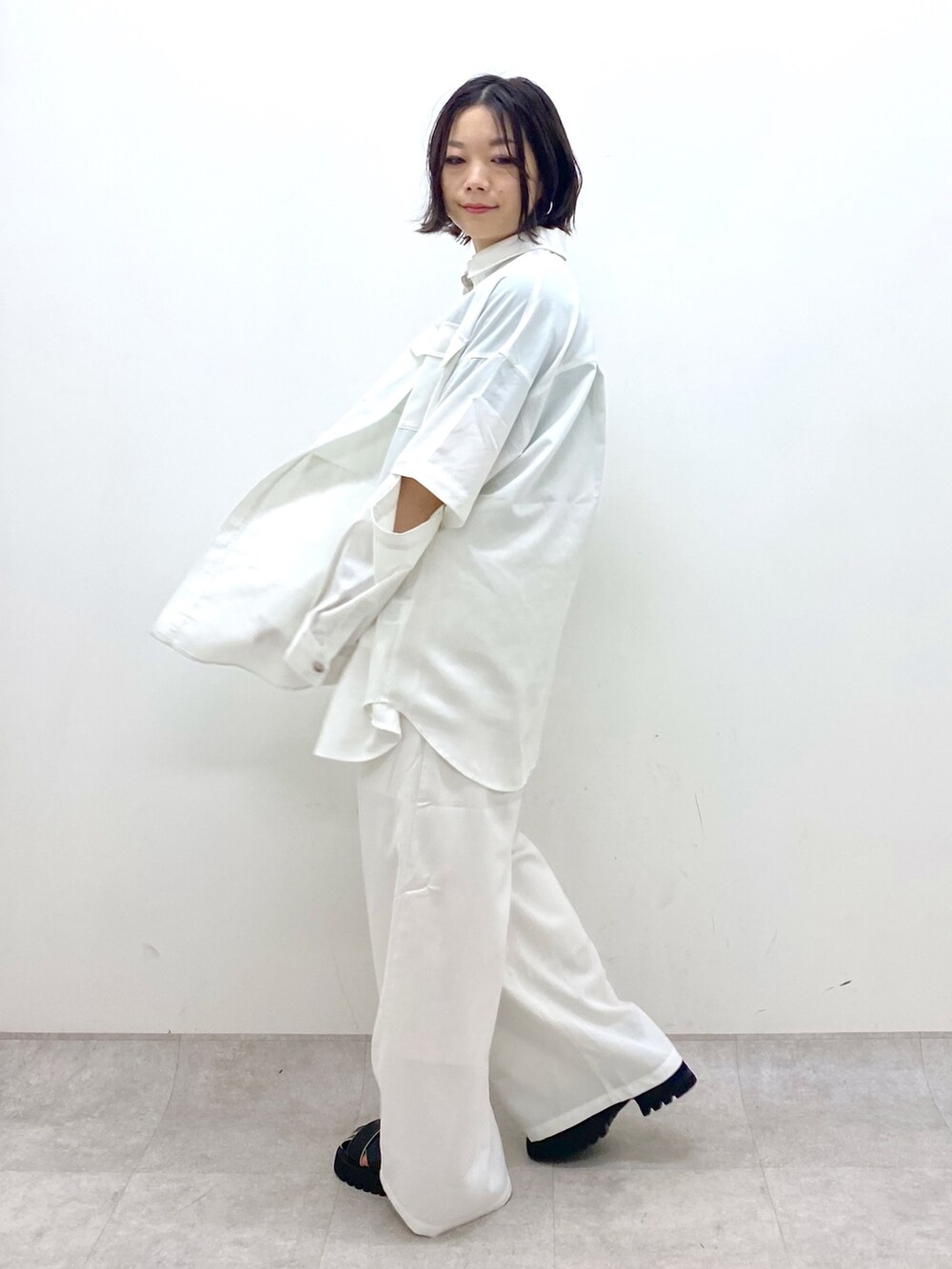 ホワイト系のパンツ、ブラック系のサンダル、ホワイト系のトップスを着用したレディースの春コーディネートの2枚目の写真