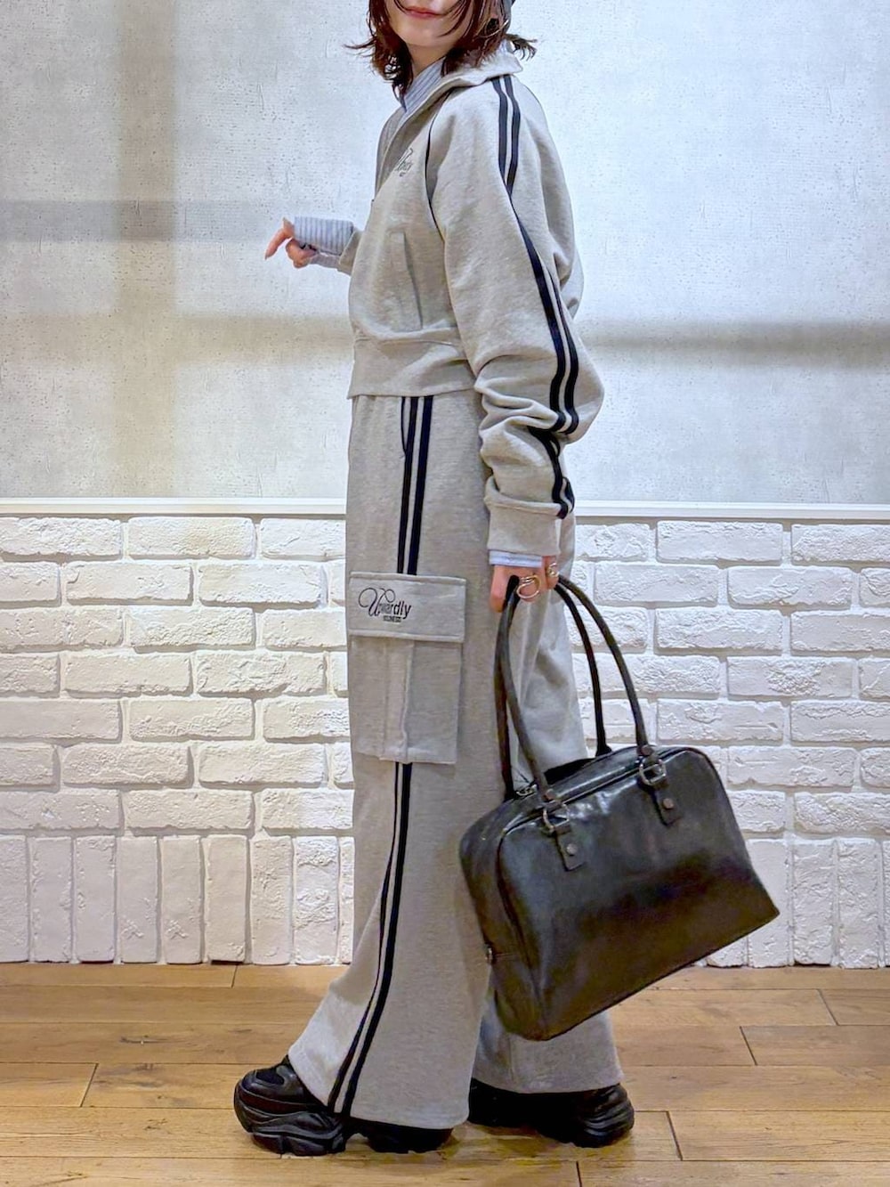 ブラック系のブーツ、ブラック系のボストンバッグ、グレー系のジャージを着用したレディースの冬コーディネートの3枚目の写真