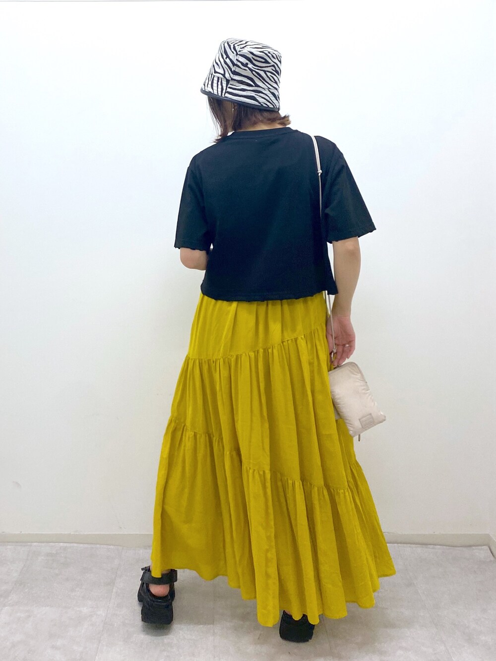 ブラック系のトップス、イエロー系のスカート、ベージュ系のショルダーバッグを着用したレディースの夏コーディネートの4枚目の写真