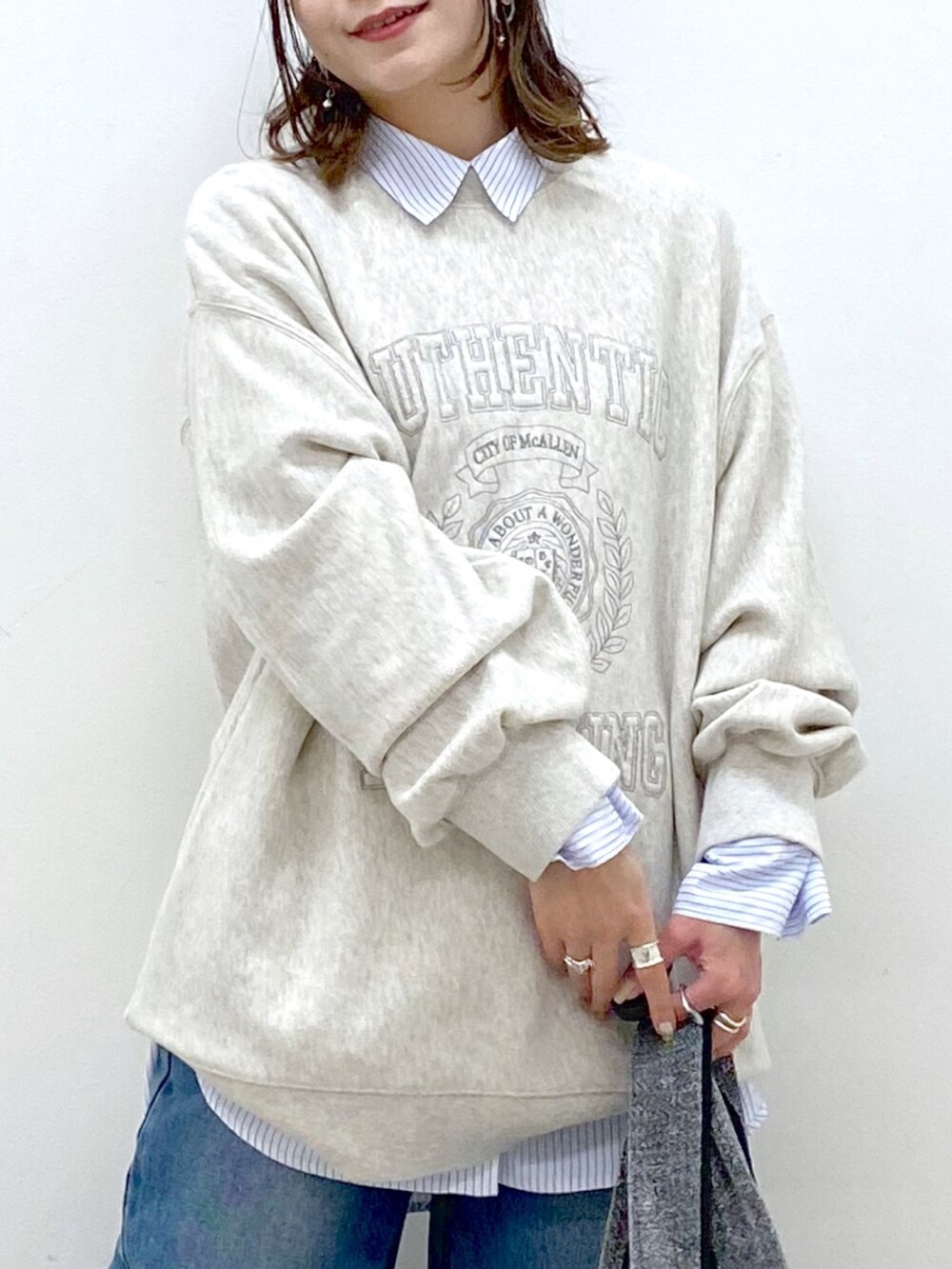 ベージュ系のスウェット、ブルー系のデニムパンツ、ブラック系のトートバッグを着用したレディースの冬コーディネートの2枚目の写真