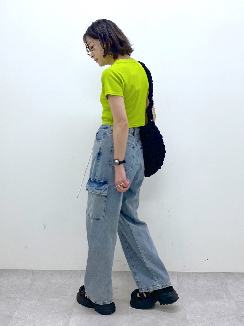 ブルー系のデニムパンツ、ブラック系のバッグ、イエロー系のTシャツ/カットソーを着用したレディースの春コーディネートの3枚目の写真