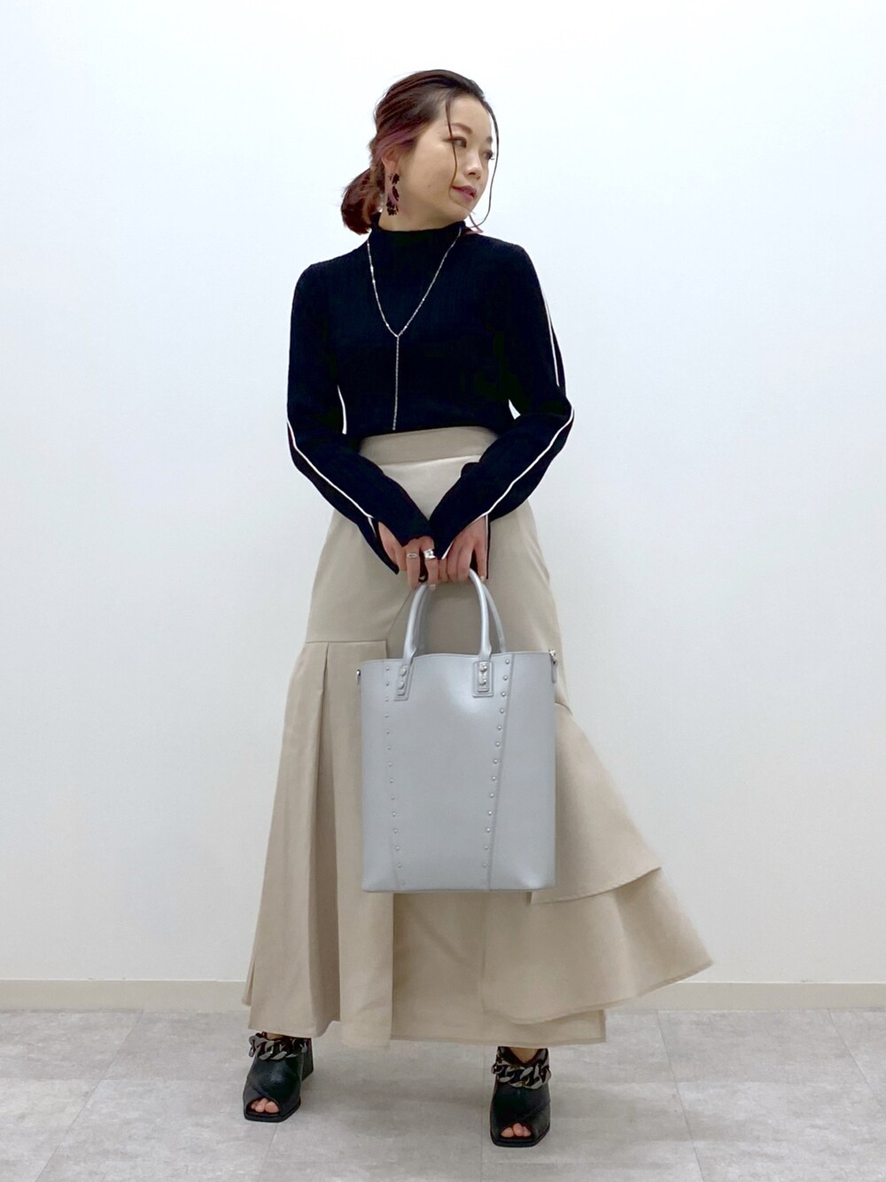 ブラック系のニット/セーター、ベージュ系のスカート、シルバー系のショルダーバッグを着用したレディースの冬コーディネートの5枚目の写真