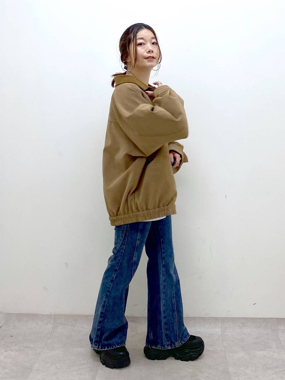 ブラック系のスニーカー、ブルー系のデニムパンツ、ブラウン系のショルダーバッグを着用したレディースの秋コーディネートの5枚目の写真