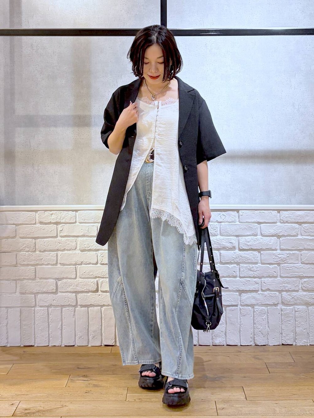 ブルー系のデニムパンツ、ブラック系のサンダル、ブラック系のテーラードジャケットを着用したレディースの春コーディネートの9枚目の写真