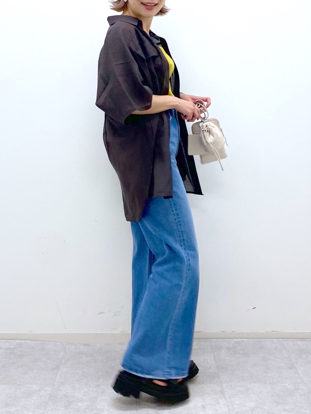 ブルー系のパンツ、イエロー系のタンクトップ、ベージュ系のショルダーバッグを着用したレディースの夏コーディネートの4枚目の写真