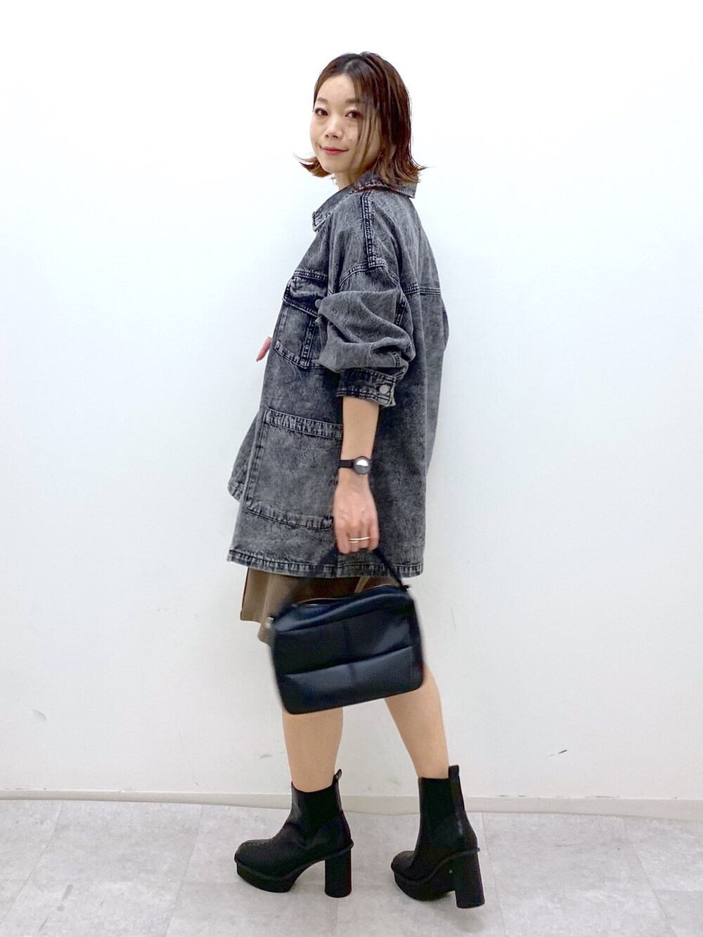 ブラウン系のパンツ、ブラック系のブーツ、ブラック系のショルダーバッグを着用したレディースの秋コーディネートの2枚目の写真