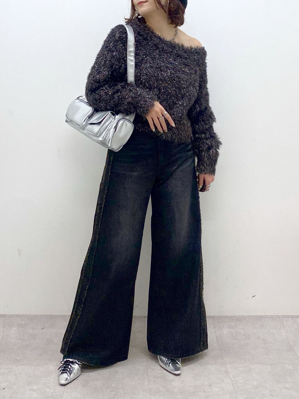 ブラック系のデニムパンツ、シルバー系のパンプス、シルバー系のショルダーバッグを着用したレディースの秋コーディネートの3枚目の写真