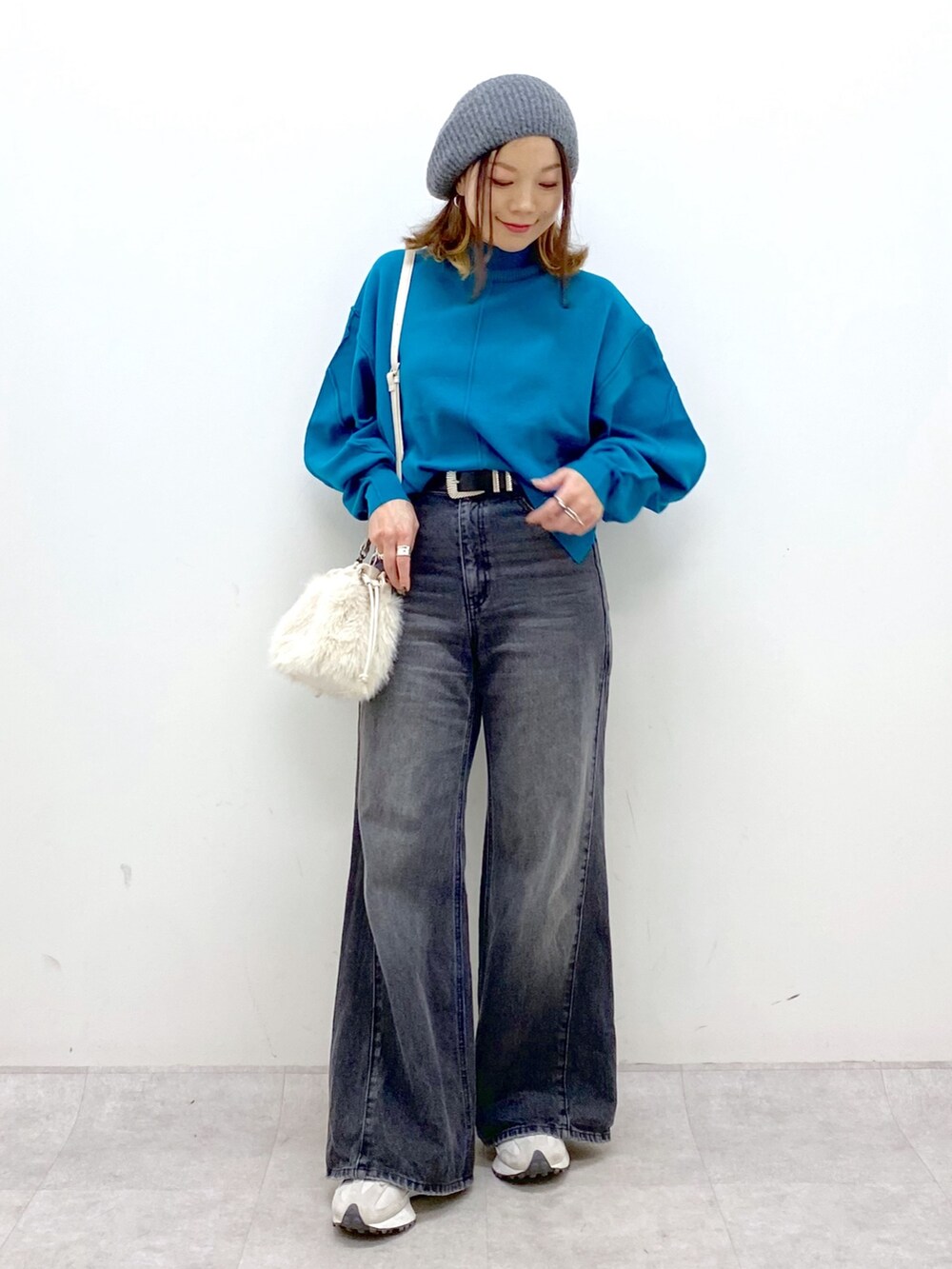 ブラック系のデニムパンツ、ホワイト系のショルダーバッグ、ブルー系のニット/セーターを着用したレディースの秋コーディネートの2枚目の写真