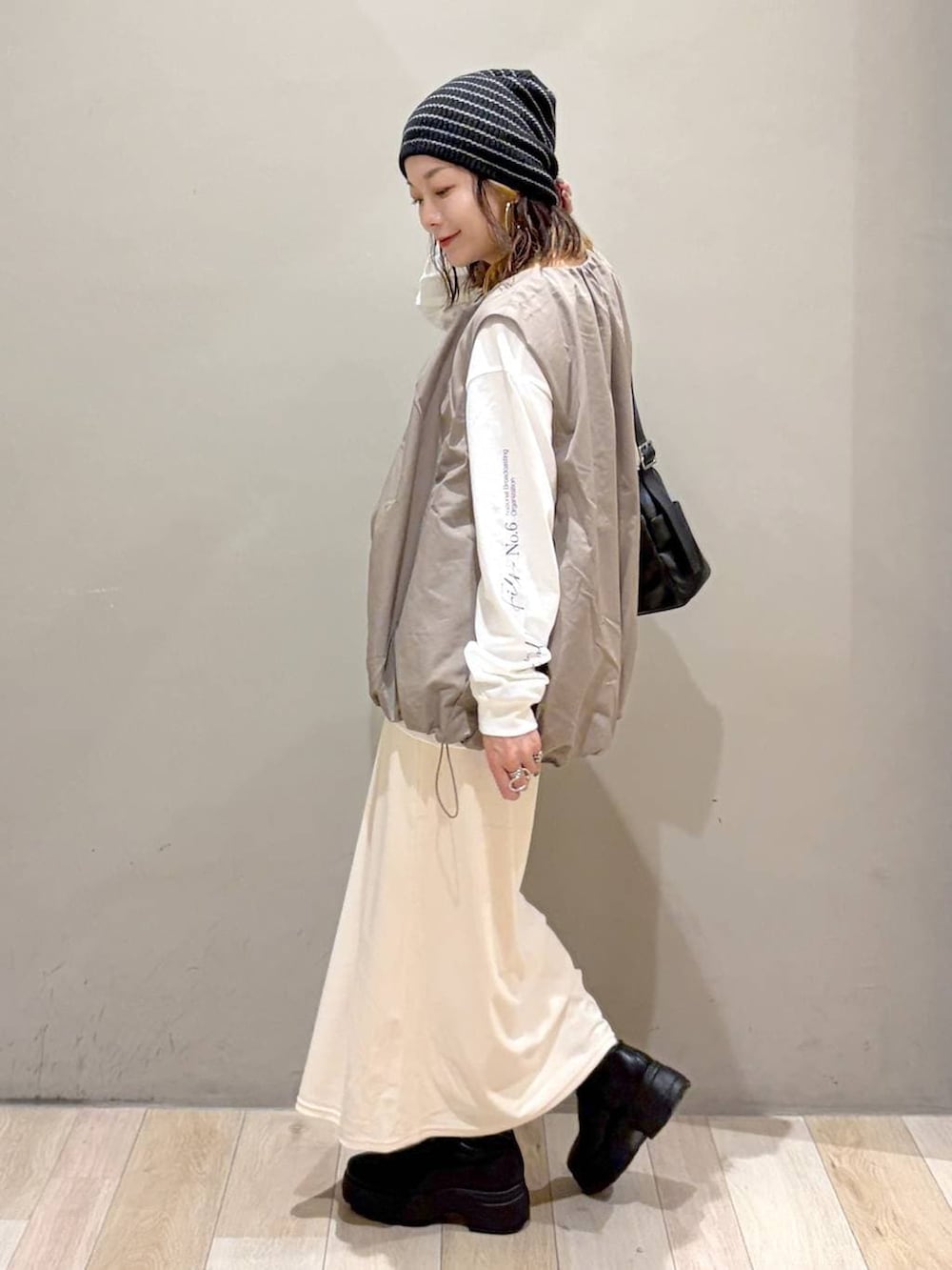 グレー系のベスト、ブラック系のブーツ、ホワイト系のTシャツ/カットソーを着用したレディースの秋コーディネートの7枚目の写真