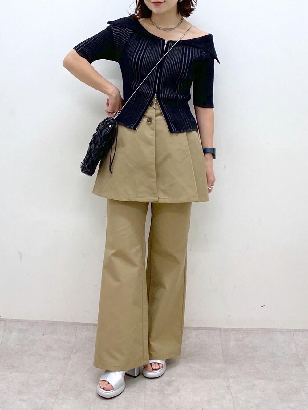 ブラック系のニット/セーター、ベージュ系のチノパンツ、ブラック系のショルダーバッグを着用したレディースの春コーディネートの3枚目の写真