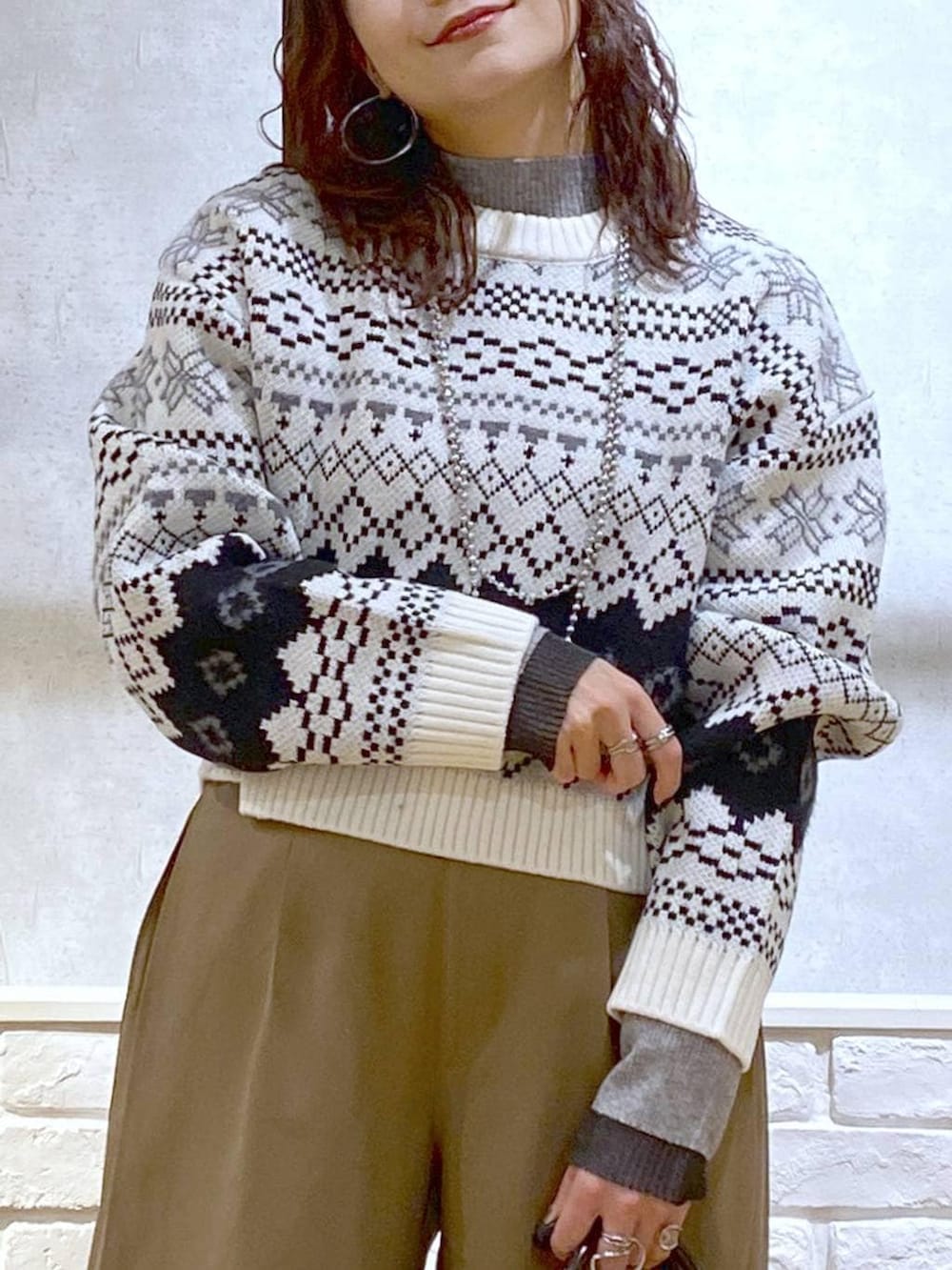 ベージュ系のスラックス、ブラウン系のボストンバッグ、グレー系のニット/セーターを着用したレディースの冬コーディネートの2枚目の写真