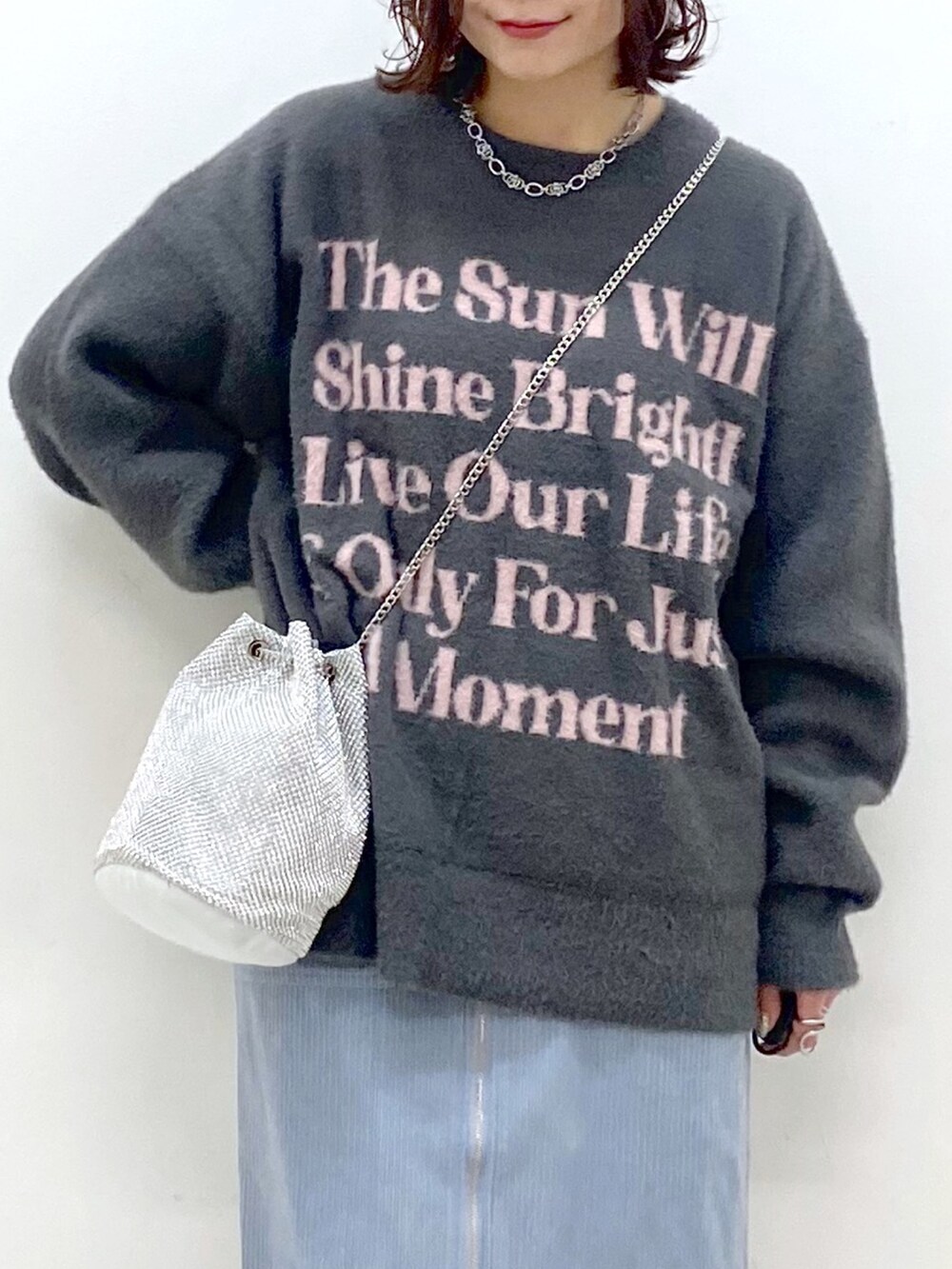 グレー系のニット/セーター、ブルー系のスカート、ブラック系のブーツを着用したレディースの秋コーディネートの2枚目の写真