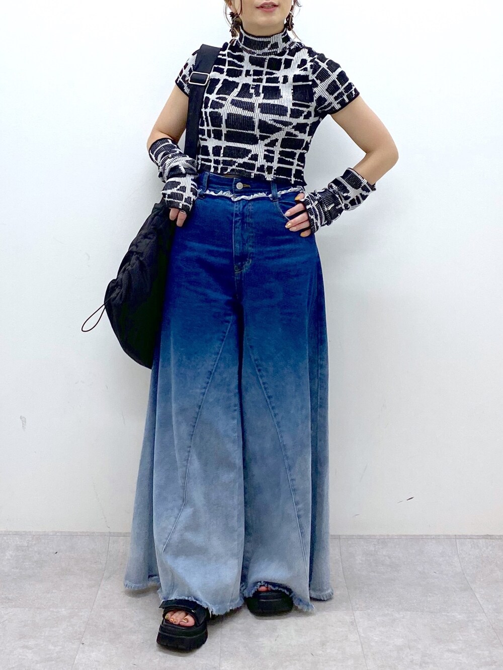 ブルー系のデニムパンツ、ブラック系のニット/セーター、ブラック系のショルダーバッグを着用したレディースの夏コーディネートの8枚目の写真