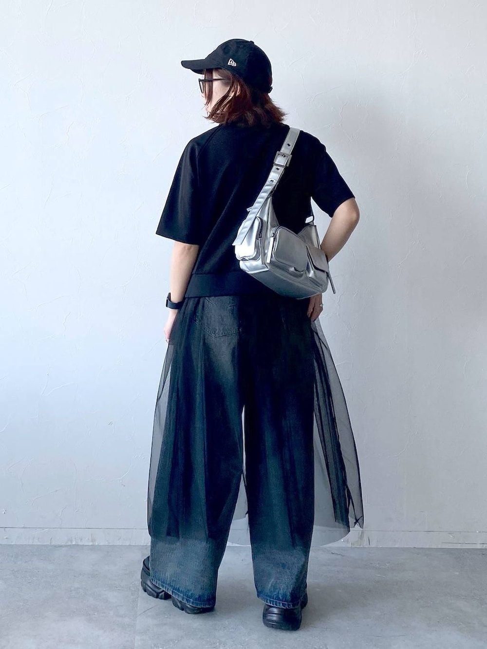 ブラック系のスニーカー、シルバー系のショルダーバッグ、ブルー系のデニムパンツを着用したレディースの夏コーディネートの6枚目の写真