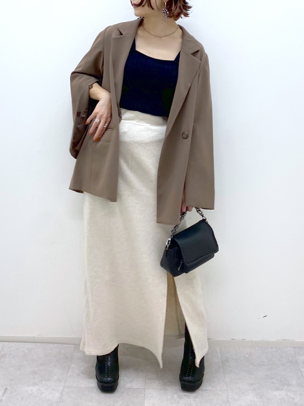 ホワイト系のスカート、ブラック系のブーツ、ブラック系のバッグを着用したレディースの秋コーディネートの5枚目の写真