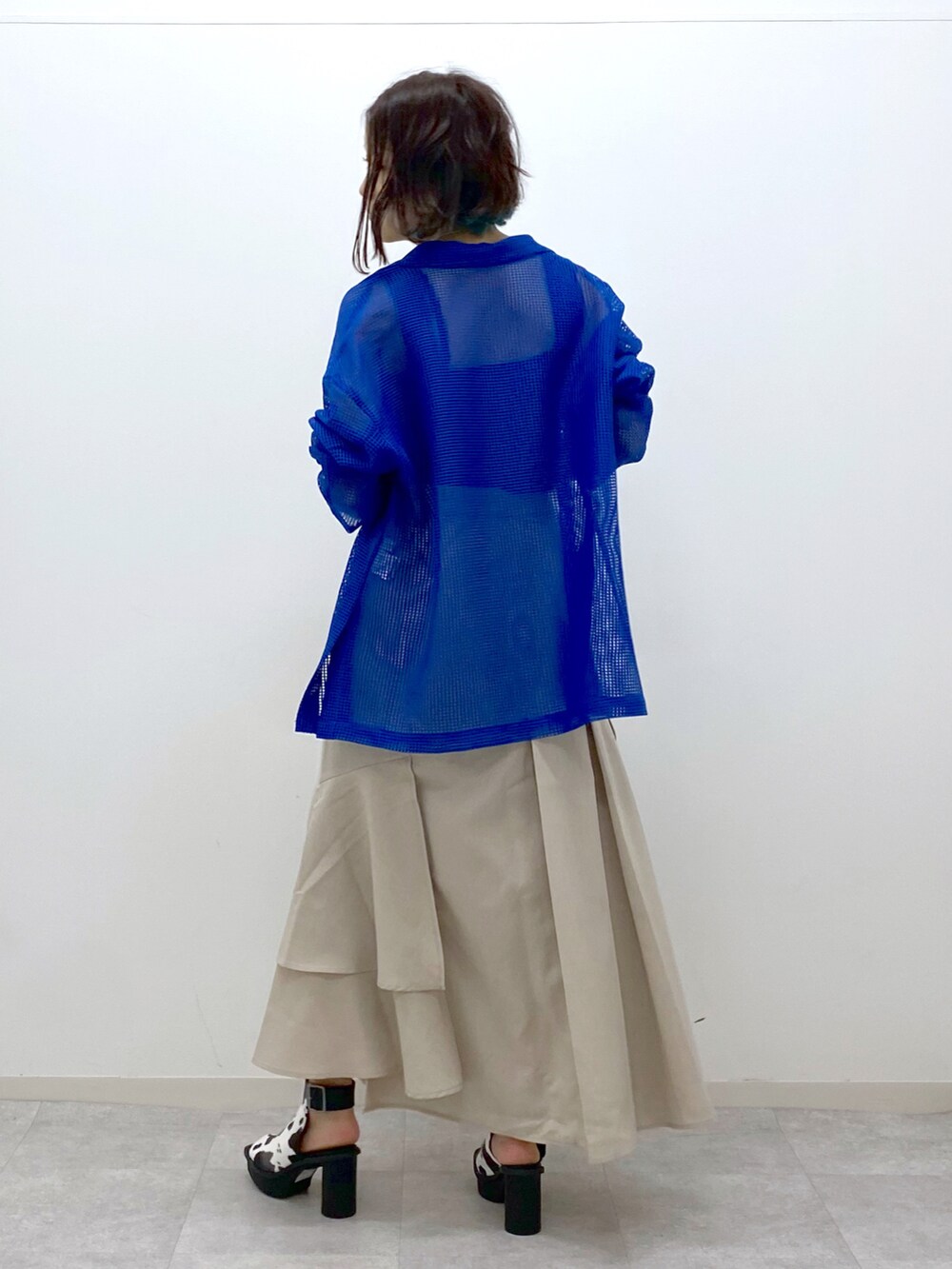 ブルー系のテーラードジャケット、ブラック系のタンクトップ、ベージュ系のスカートを着用したレディースの春コーディネートの4枚目の写真