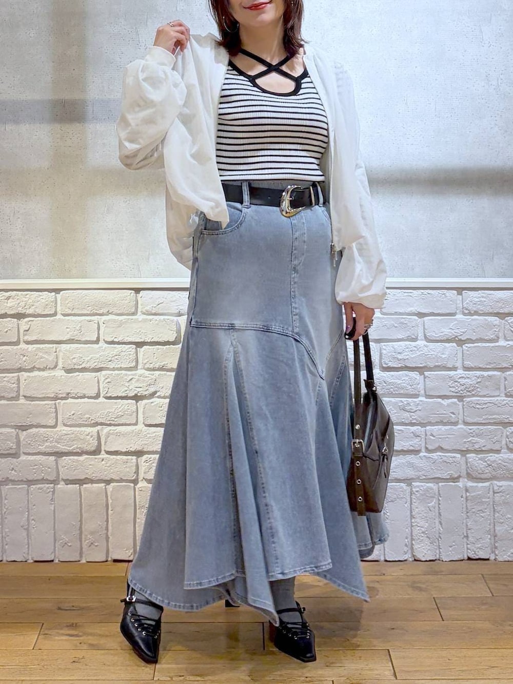 ブラウン系のハンドバッグ、ホワイト系のニット/セーター、ブラック系のサンダルを着用したレディースの春コーディネートの3枚目の写真