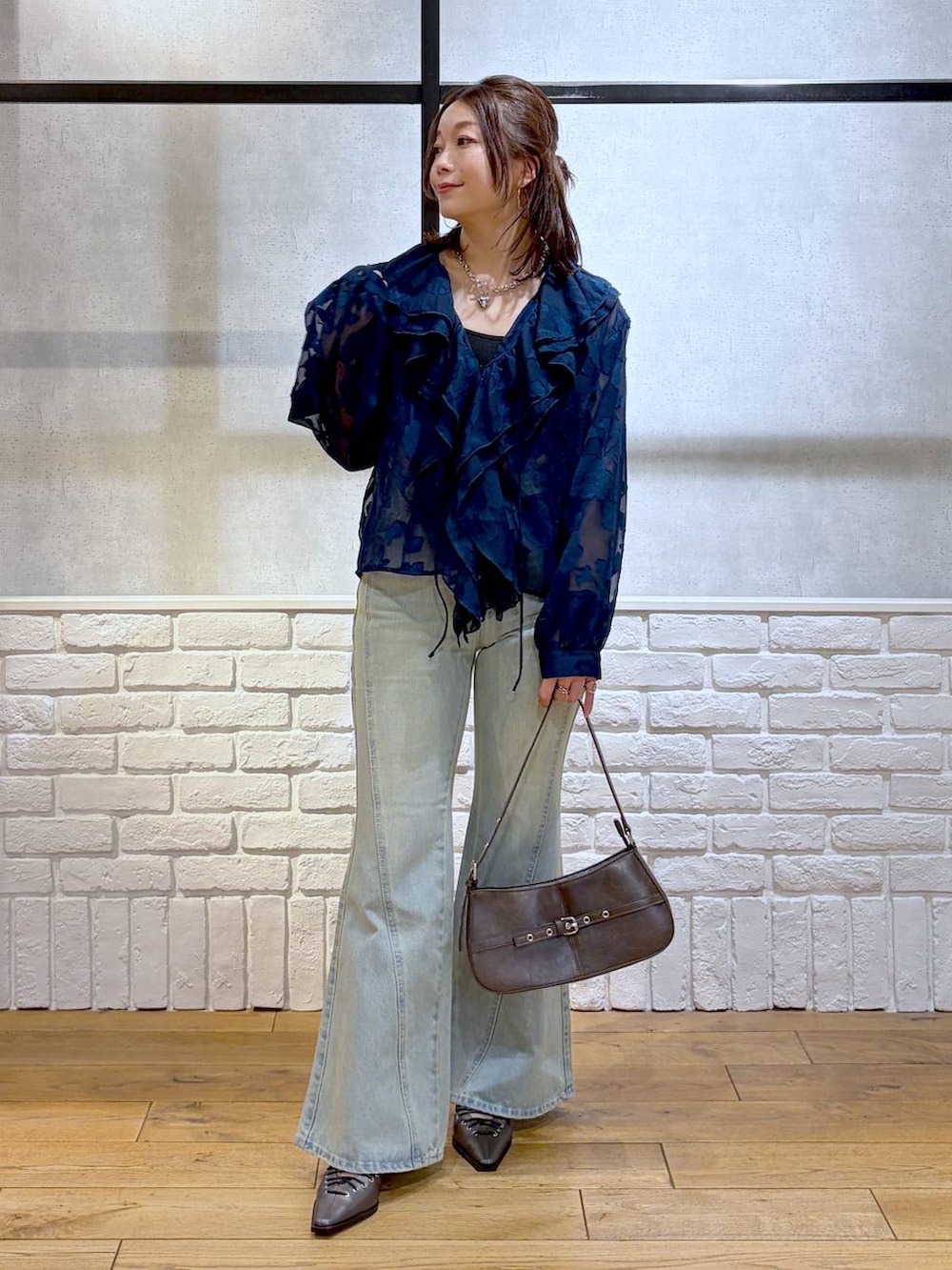ブラック系のキャミソール、ブルー系のデニムパンツ、ブラウン系のハンドバッグを着用したレディースの春コーディネートの4枚目の写真