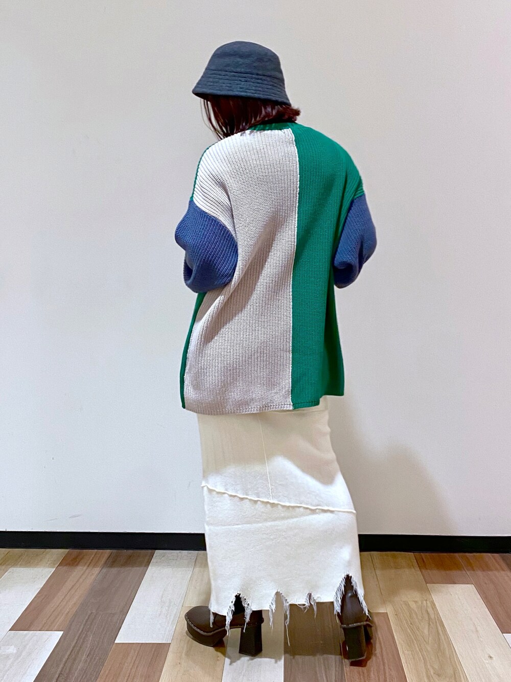 ブラウン系のブーツ、ホワイト系のスカート、グリーン系のニット/セーターを着用したレディースの冬コーディネートの4枚目の写真