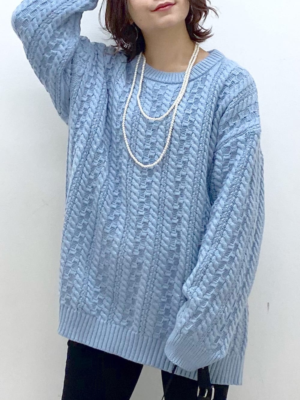 グリーン系のニット/セーター、ブラック系のショルダーバッグ、ブラック系のデニムパンツを着用したレディースの冬コーディネートの2枚目の写真