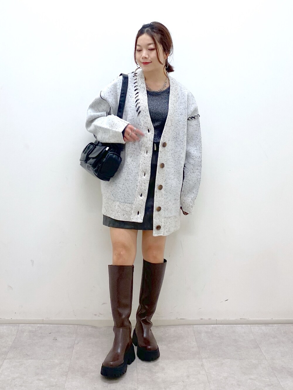 ホワイト系のニット/セーター、シルバー系のTシャツ/カットソー、ブラック系のスカートを着用したレディースの秋コーディネートの4枚目の写真