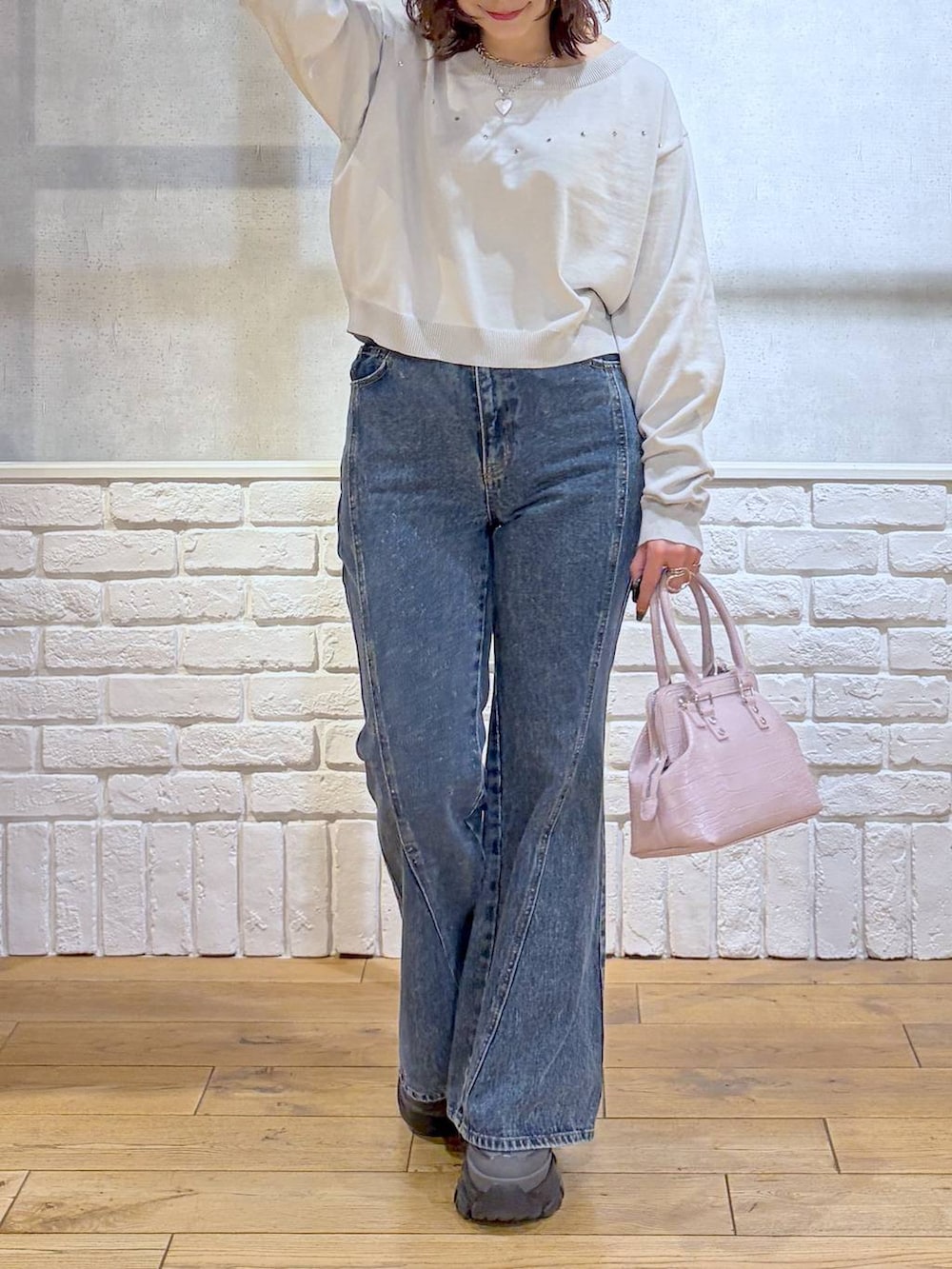 グレー系のスニーカー、ブルー系のデニムパンツ、ピンク系のハンドバッグを着用したレディースの冬コーディネートの3枚目の写真