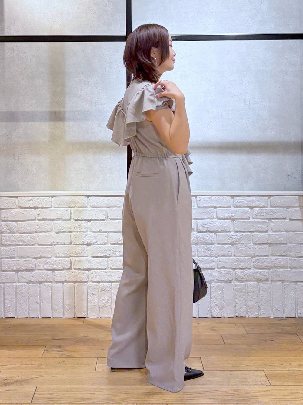 ブラック系のハンドバッグ、ブラック系のサンダル、ベージュ系のサロペット/オーバーオールを着用したレディースの春コーディネートの7枚目の写真