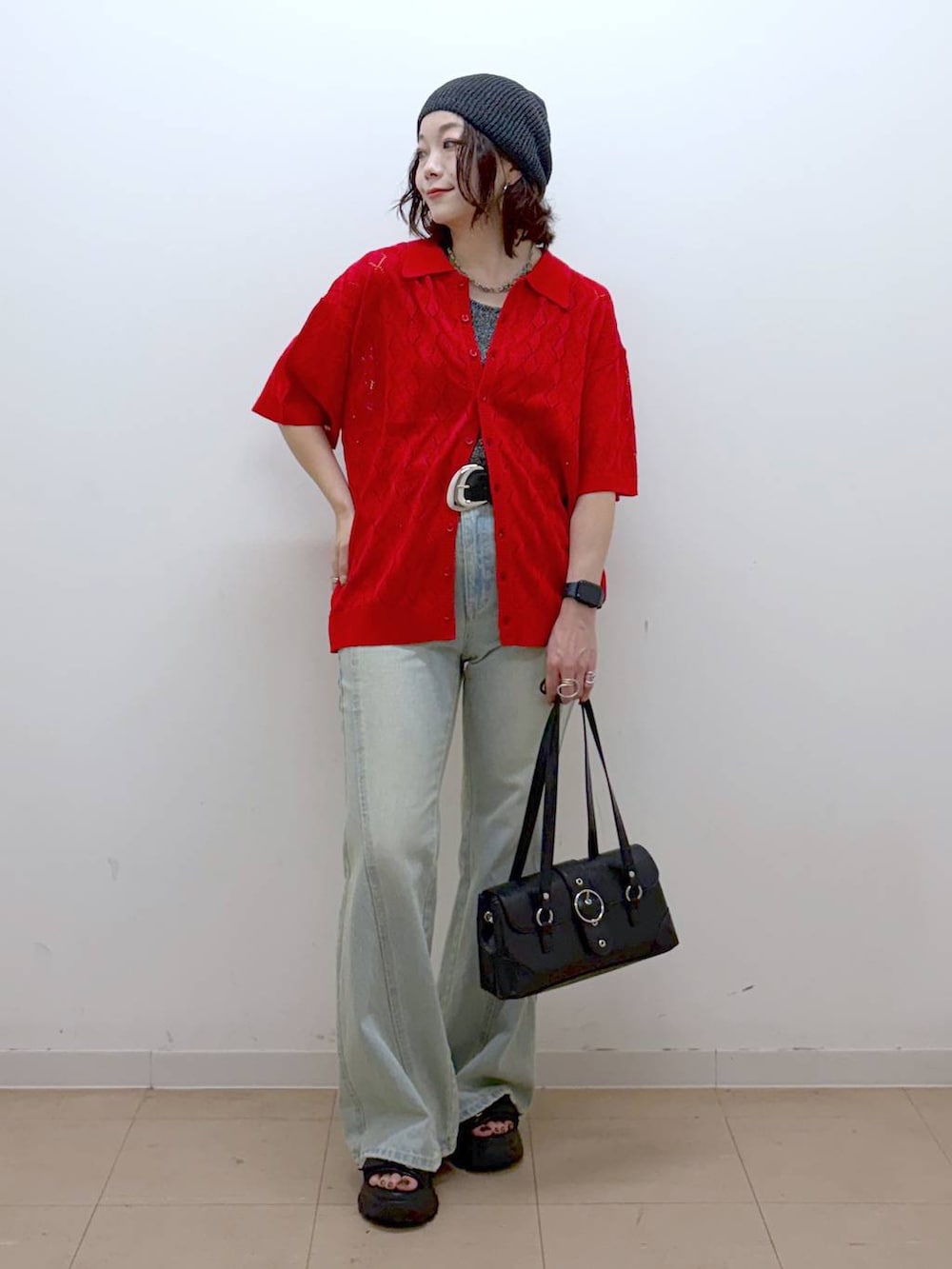 レッド系のポロシャツ、ブルー系のデニムパンツ、ブラック系のサンダルを着用したレディースの夏コーディネートの4枚目の写真