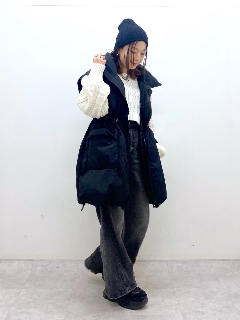 ブラック系のブルゾン、ホワイト系のニット/セーター、ブラック系のデニムパンツを着用したレディースの冬コーディネートの2枚目の写真