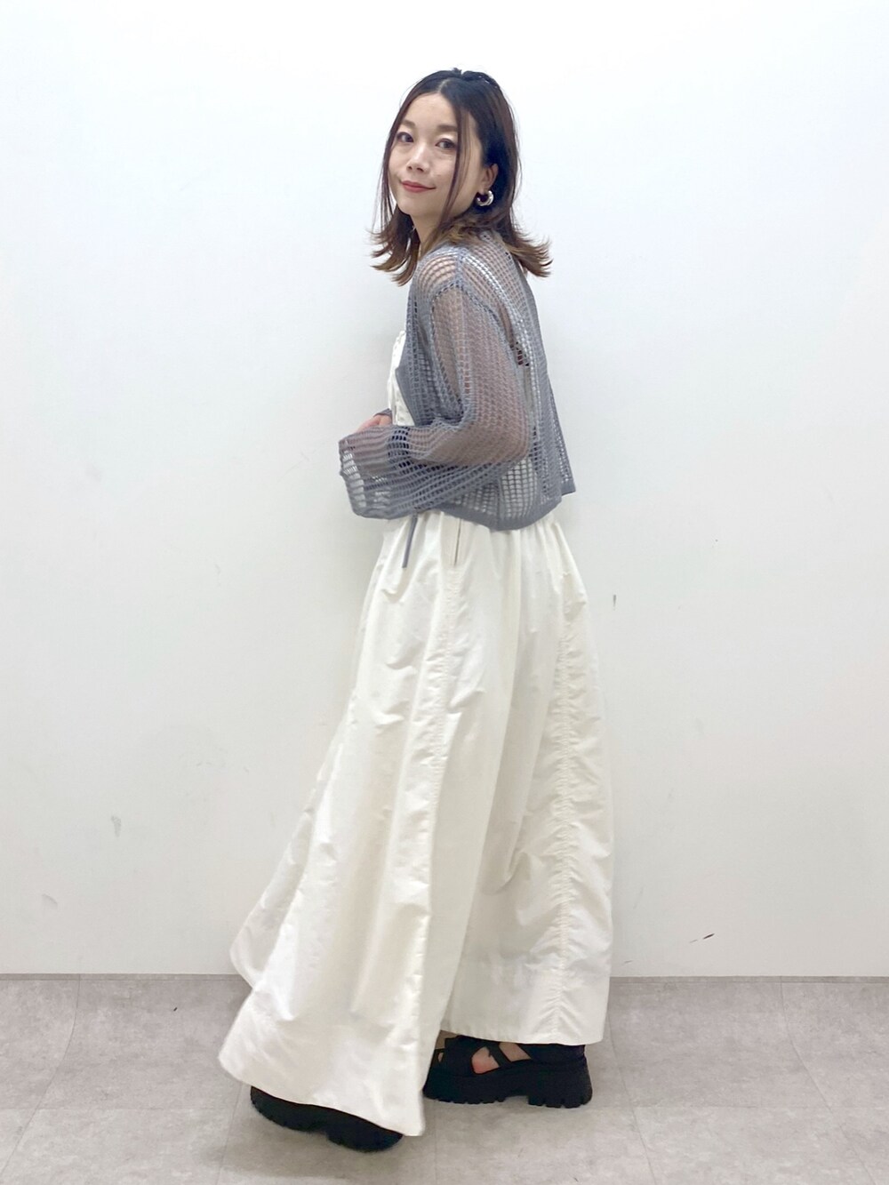 ホワイト系のワンピース、グレー系のカーディガン/ボレロ、ブラック系のサンダルを着用したレディースの春コーディネートの5枚目の写真